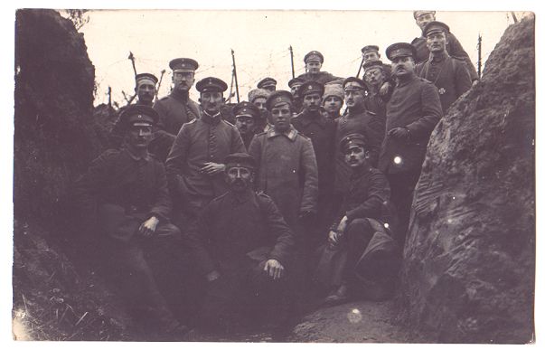 About 20 soldiers grouped together in a muddy trench, posing proudly for the camera.