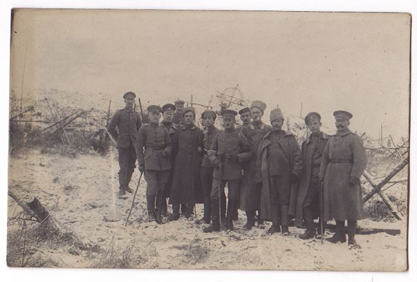Twelve officers and NCOs stand in a group.  Snow lies thickly on the ground, and behind them are looped and tangled lines of snow-covered barbed wire.