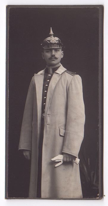 A full length, formal portrait of a young officer in dress uniform with coat.